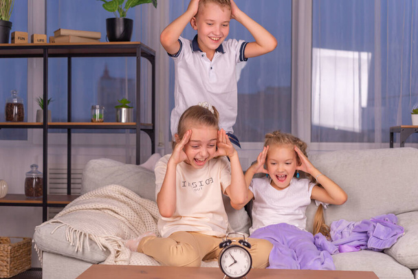 uma menina e um menino escolares com um despertador que chama em voz alta não quer acordar de manhã - Foto, Imagem