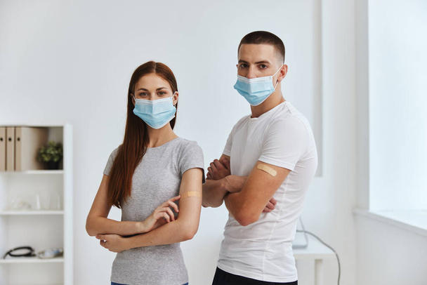 γυναίκες και άνδρες φορώντας ιατρικές μάσκες και με κολλητική ταινία στους ώμους τους στο νοσοκομειακό διαβατήριο covid - Φωτογραφία, εικόνα