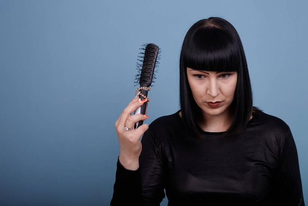 portrait of a beautiful girl with a comb, preparing for a photo shoot on a blue background - Photo, Image
