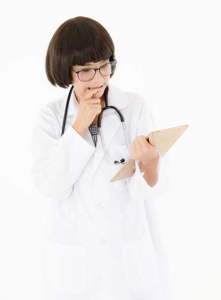 Beyaz önlüklü, gözlüklü, boyunda steteskop olan profesyonel Asyalı kadın doktor klinikte çalışırken düşünceli ve ciddi bir şekilde dijital tablet verilerini kontrol ediyor. - Fotoğraf, Görsel