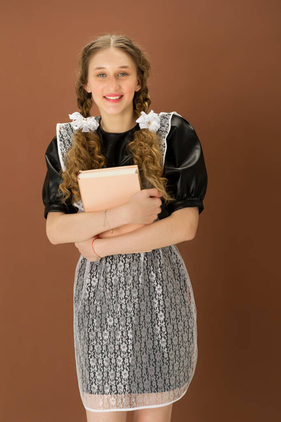 Cheerful girl in school uniform holding close book - Fotografie, Obrázek