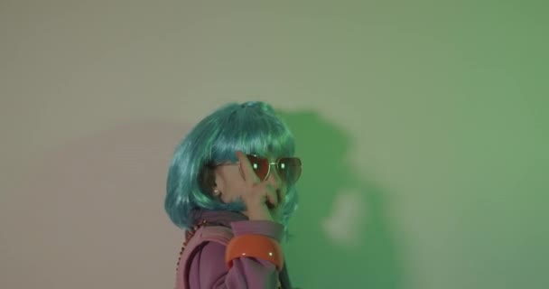 Kids photo shoot. Portrait of a glamour child wearing colorful wig on disco light background - Felvétel, videó