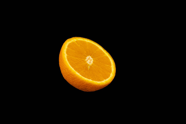 A closeup shot of a sliced orange isolated on a dark background - Foto, Imagem