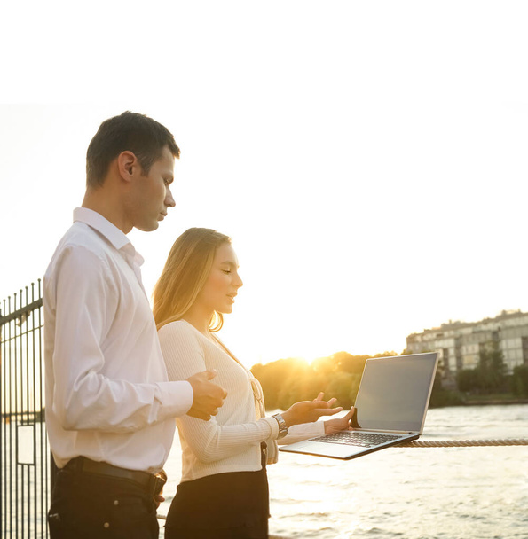 Young couple standing on coast   working with laptop and looking at the screen.  - Foto, Imagen