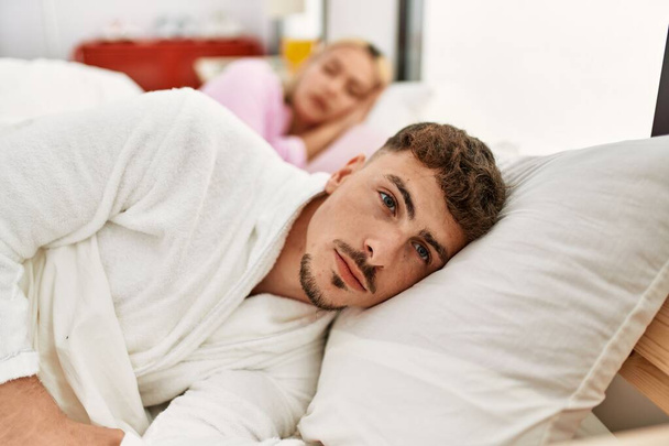 Nuori valkoihoinen pari makaa sängyllä. Mies katsoo kameraan kotona.. - Valokuva, kuva
