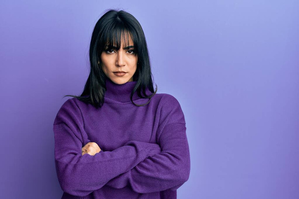 Young brunette woman with bangs wearing turtleneck sweater skeptic and nervous, disapproving expression on face with crossed arms. negative person.  - Foto, Imagen