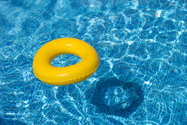Un flotador amarillo de la piscina, anillo de la piscina en la refrescante piscina azul fresco
 - Foto, imagen
