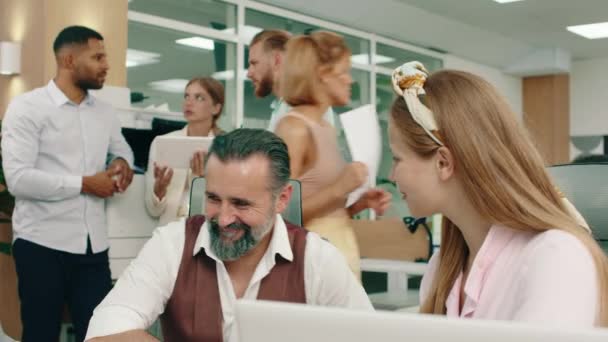 A manager is at his office table talking seriously about the work to his colleague, in the back a woman manager in a white suit is talking to her other two colleagues about the work on the tablet - Filmagem, Vídeo