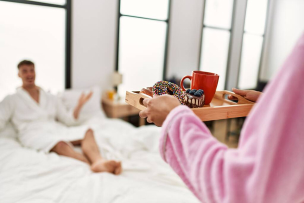Femme surprenant son petit ami prendre le petit déjeuner sur le lit à la maison. - Photo, image