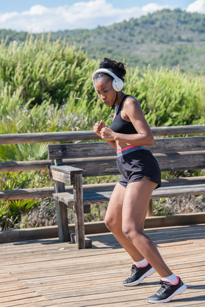Duro afro americano donna con cuffie esercizio all'aperto: Esercizio e concetto di forza. - Foto, immagini