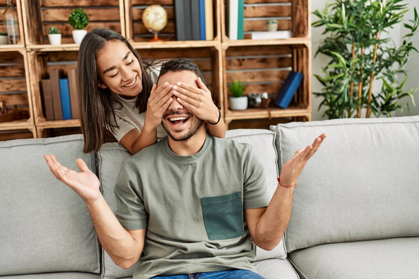 Woman surprising her boyfriend with hands on eyes at home. - 写真・画像