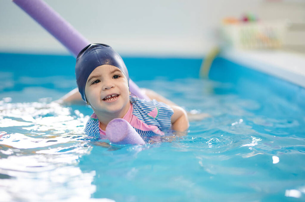 A gyermek úszik a lebegő csövön. A kölyök úszni tanul.  - Fotó, kép