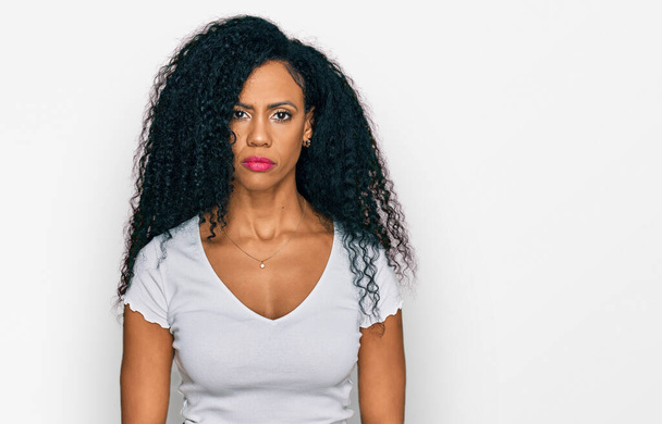 Middle age african american woman wearing casual white t shirt relaxed with serious expression on face. simple and natural looking at the camera.  - Foto, imagen