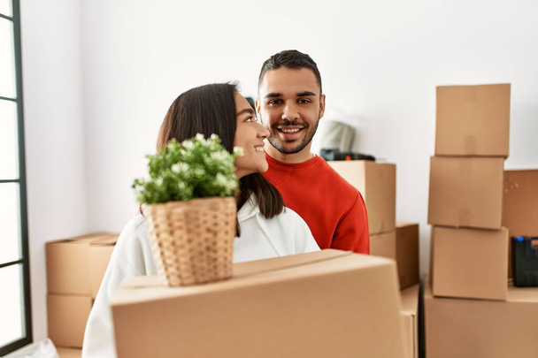 Young latin couple smiling happy holding cardboard box at new home. - Photo, Image