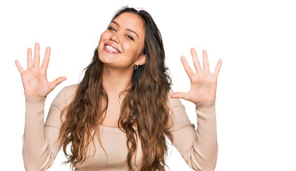 Menina hispânica jovem vestindo roupas casuais mostrando e apontando para cima com os dedos número dez, sorrindo confiante e feliz.  - Foto, Imagem