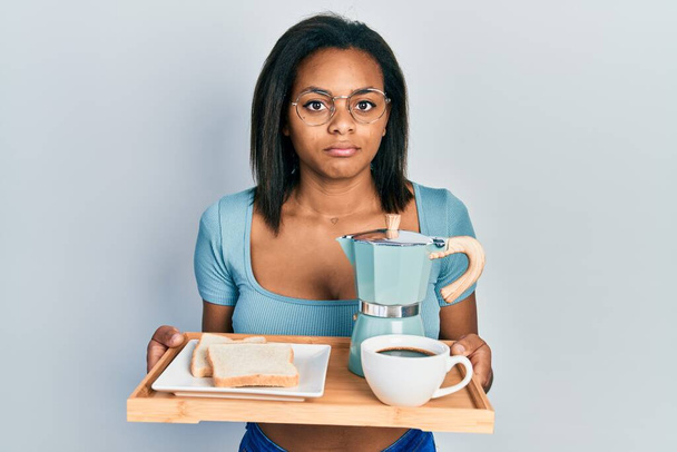 Genç Afro-Amerikalı kız elinde kahvaltı tepsisiyle depresif ve üzüntülü, sinirli ve korkmuş bir şekilde ağlıyor. hüzünlü ifade.  - Fotoğraf, Görsel