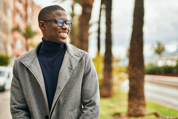 Jovem afro-americano sorrindo feliz de pé na cidade - Foto, Imagem