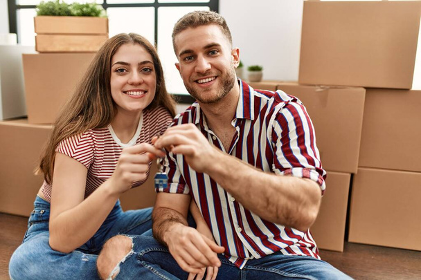 Young caucasian couple smiling happy holding key of new home. - Fotó, kép