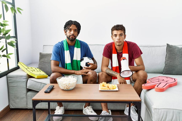 Молоді іспаномовні брати футбольні хулігани тримають м'яч і мегафон мислення ставлення і тверезий вираз, дивлячись на себе впевнено
  - Фото, зображення