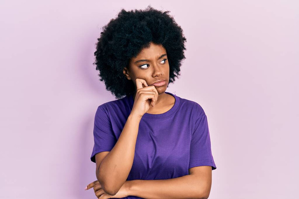 Jeune femme afro-américaine portant des vêtements décontractés visage sérieux penser à la question avec la main sur le menton, réfléchi sur l'idée déroutante  - Photo, image