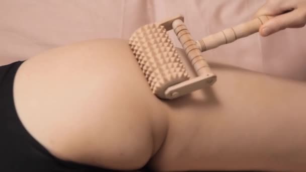 Masajista femenina haciendo masaje anticelulitis en muslo de mujer. Tratamiento de Maderoterapia. Tratamientos de spa, salud, belleza, dieta. Primer plano de los muslos del cliente y las manos del masajista - Metraje, vídeo