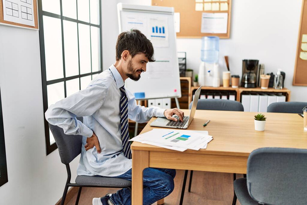 Junger hispanischer Geschäftsmann mit Rückenschmerzen arbeitet im Büro. - Foto, Bild