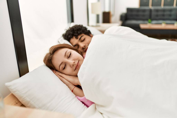 Junges Paar lächelt glücklich schlafend auf dem Bett im Schlafzimmer. - Foto, Bild