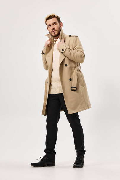 pohledný muž v béžové kabát móda moderní styl boční pohled plné délky - Fotografie, Obrázek