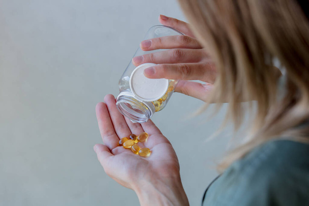 femme déverse dans un bocal pilules avec de l'huile de foie de morue
 - Photo, image