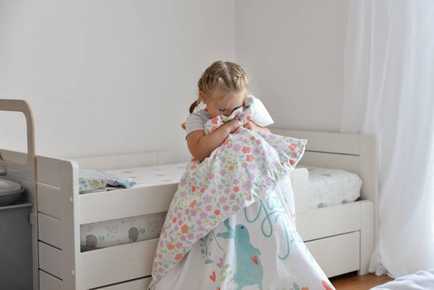 A girl makes a bed in the children room - Fotó, kép