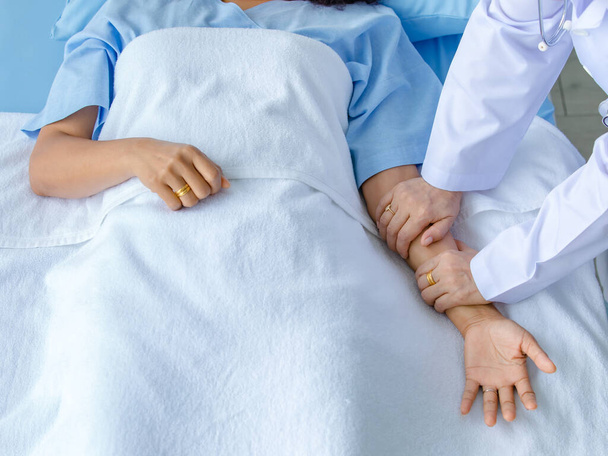 Arzt hält Hand des Patienten auf dem Bett im Krankenhaus und checkt Nervensystem für Heilung und Behandlung. Konzept des Guillain-Barre-Syndroms und der Taubheitserkrankung der Hände oder Nebenwirkung des Impfstoffs. - Foto, Bild