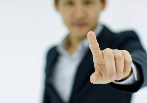 Geïsoleerde studio close-up shot hand van Aziatische succesvolle professionele zakenman draagt zwarte formele pak staan in wazig witte achtergrond met index vinger wijzen aanraken kiezen lege ruimte. - Foto, afbeelding