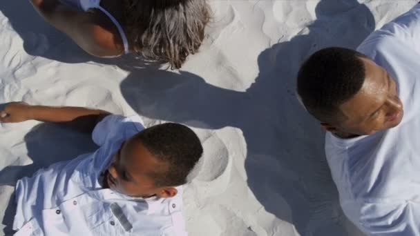 Родители и сын лежат на песке
 - Кадры, видео