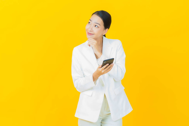 Portret piękna młoda azjatycka kobieta uśmiech z inteligentnym telefonem komórkowym na tle koloru - Zdjęcie, obraz