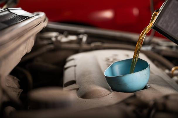 Auto mechanic pours oil into a car engine. - Foto, Imagem
