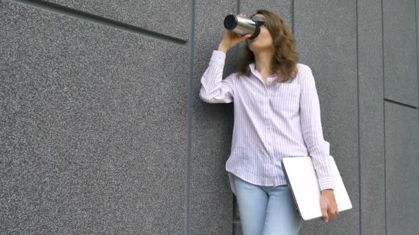 Frauenporträt einer jungen Frau mit silbernem Laptop und Tasse Kaffee, die morgens in der Nähe einer dunkelgrauen Wand auf ein Treffen wartet, Fernjob, Kaffeepause, intelligentes Studentenkonzept - Filmmaterial, Video