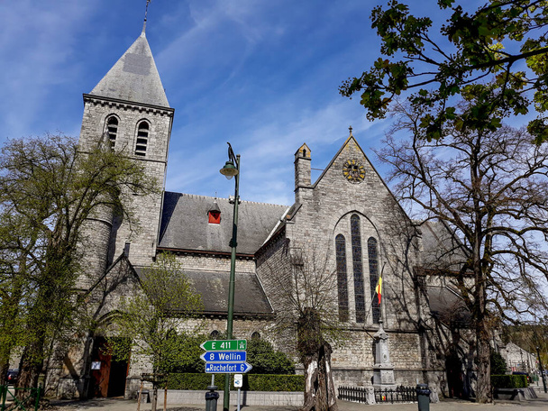 Европейская церковь построена из темного кирпича с готическими арками и витражами на улице с деревьями и указателями, указывающими на дороги и населенные пункты - Фото, изображение