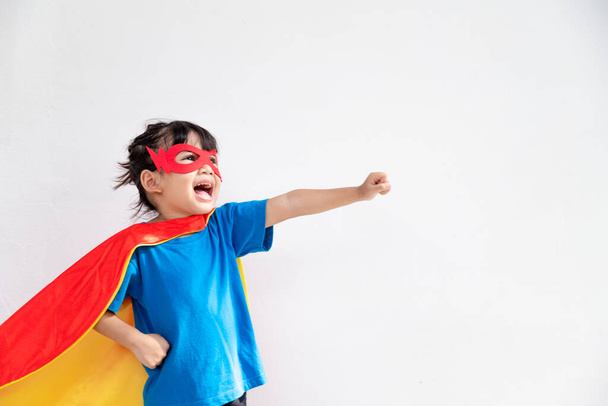 La bambina gioca a fare la supereroina. Bambino sullo sfondo bianco. Ragazza potere concetto - Foto, immagini