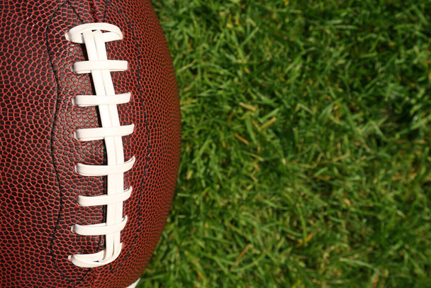 Top view of American football ball on green field grass, closeup. Space for text - Fotografie, Obrázek
