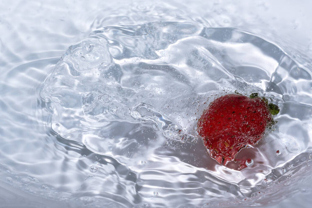 Dojrzała słodka truskawka jest myta w czystej zimnej wodzie z rozpryskami i bąbelkami zbliżenie - Zdjęcie, obraz