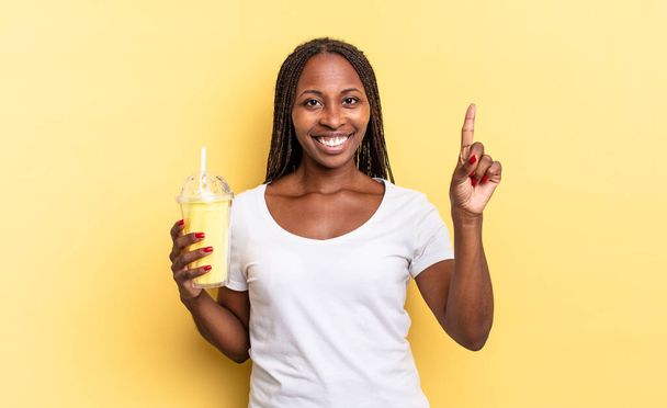 smiling and looking friendly, showing number one or first with hand forward, counting down. milkshake concept - Fotó, kép