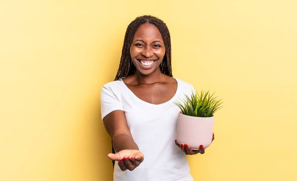 smiling happily with friendly, confident, positive look, offering and showing an object or concept holding a plant pot - Foto, Bild