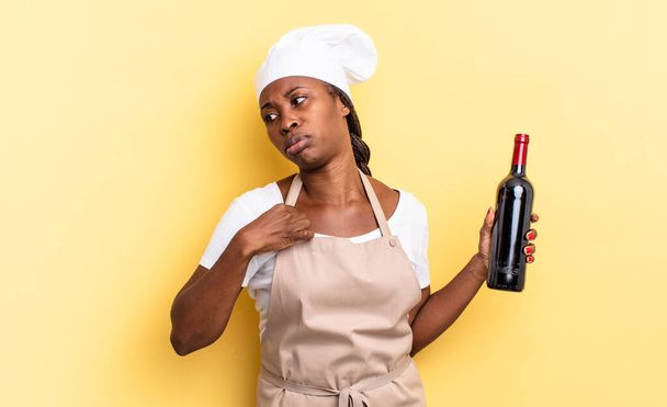 musta afro kokki nainen tunne stressaantunut, ahdistunut, väsynyt ja turhautunut, vetämällä paita kaula, näyttää turhautunut ongelma. viinipullon käsite - Valokuva, kuva