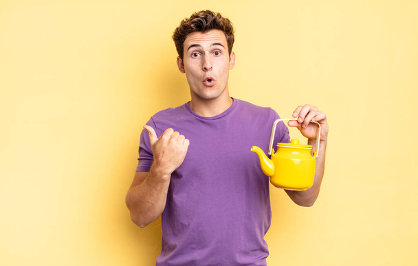 looking astonished in disbelief, pointing at object on the side and saying wow, unbelievable. teapot concept - Фото, изображение