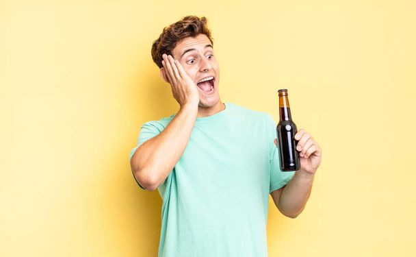 feeling happy, excited and surprised, looking to the side with both hands on face. beer bottle concept - Foto, Bild