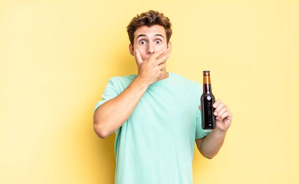 covering mouth with hands with a shocked, surprised expression, keeping a secret or saying oops. beer bottle concept - Фото, зображення