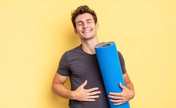 laughing out loud at some hilarious joke, feeling happy and cheerful, having fun. yoga mat concept - Фото, изображение