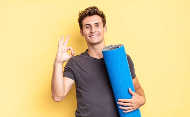 feeling happy, relaxed and satisfied, showing approval with okay gesture, smiling. yoga mat concept - Fotoğraf, Görsel