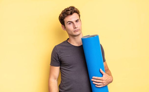 feeling sad, upset or angry and looking to the side with a negative attitude, frowning in disagreement. yoga mat concept - Фото, изображение