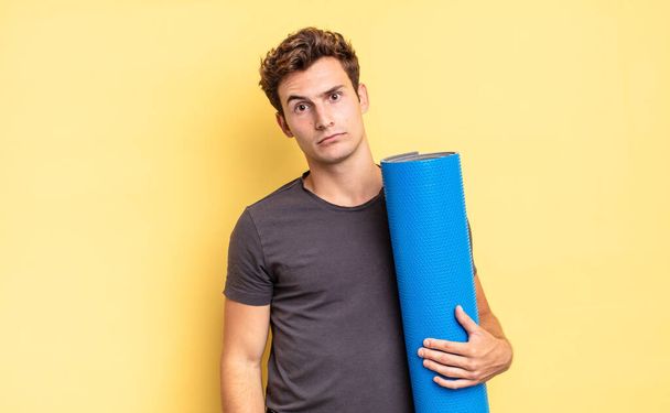 feeling puzzled and confused, with a dumb, stunned expression looking at something unexpected. yoga mat concept - Valokuva, kuva